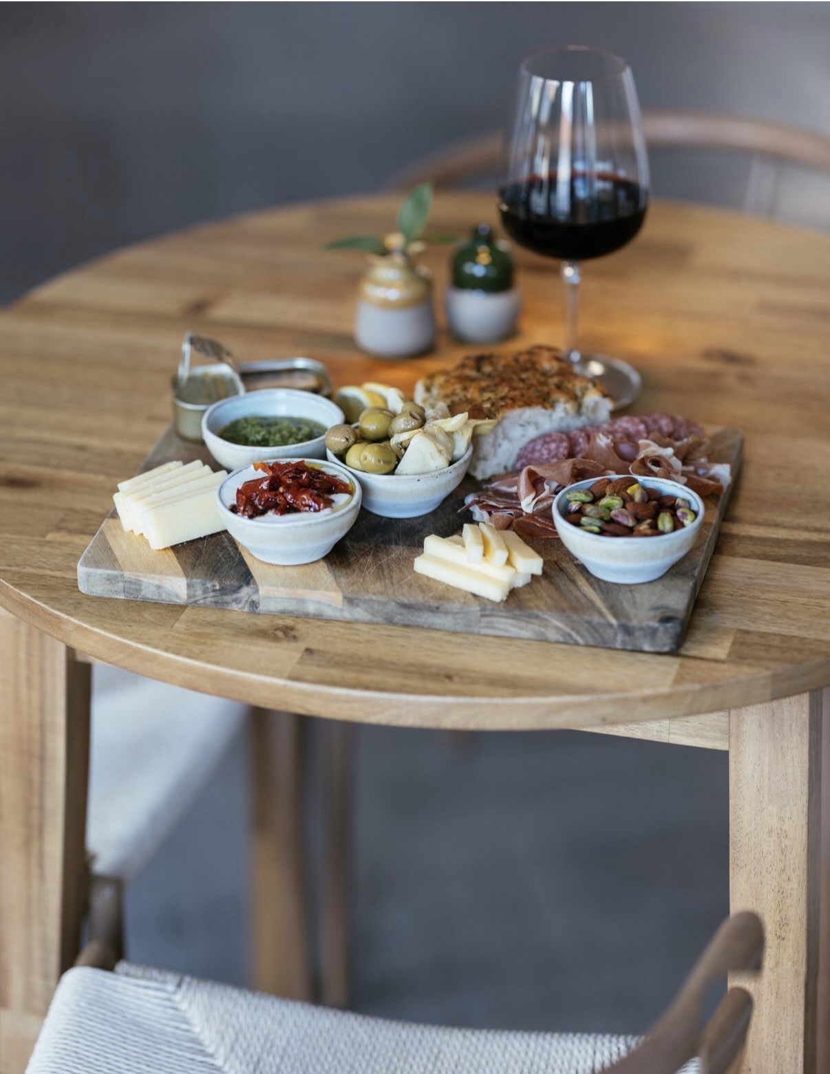Charcuteribræt med ost, skinke, focaccia, nødder og oliven samt et glas rødvin